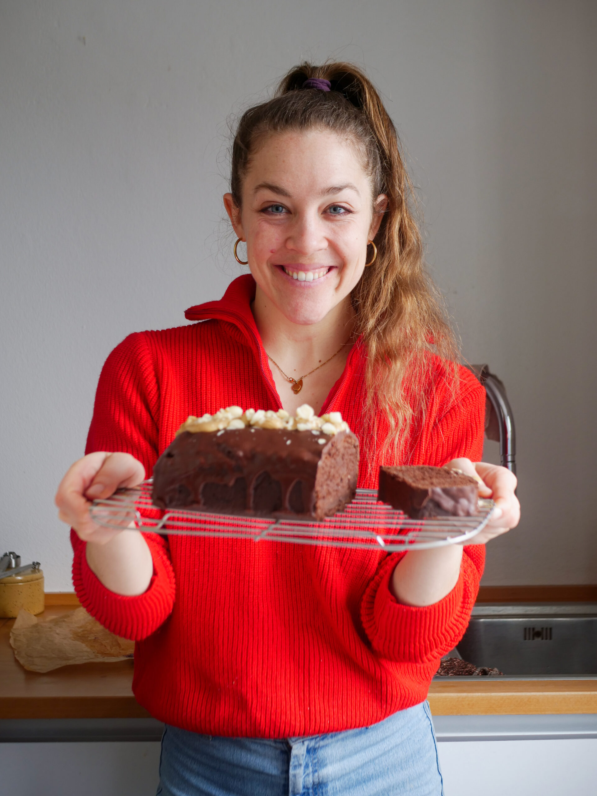 Sarah hält strahlend den Schokokuchen in den Händen