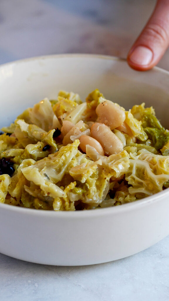 Wirsing in Kokosmilch mit Bohnen in einer Schüssel serviert